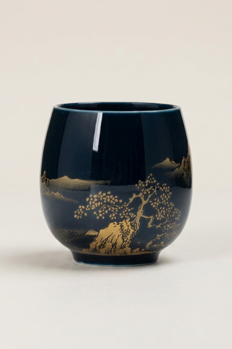 Taza de té japonesa negra con paisaje dorado de lago