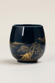 Taza de té japonesa negra con paisaje dorado de lago