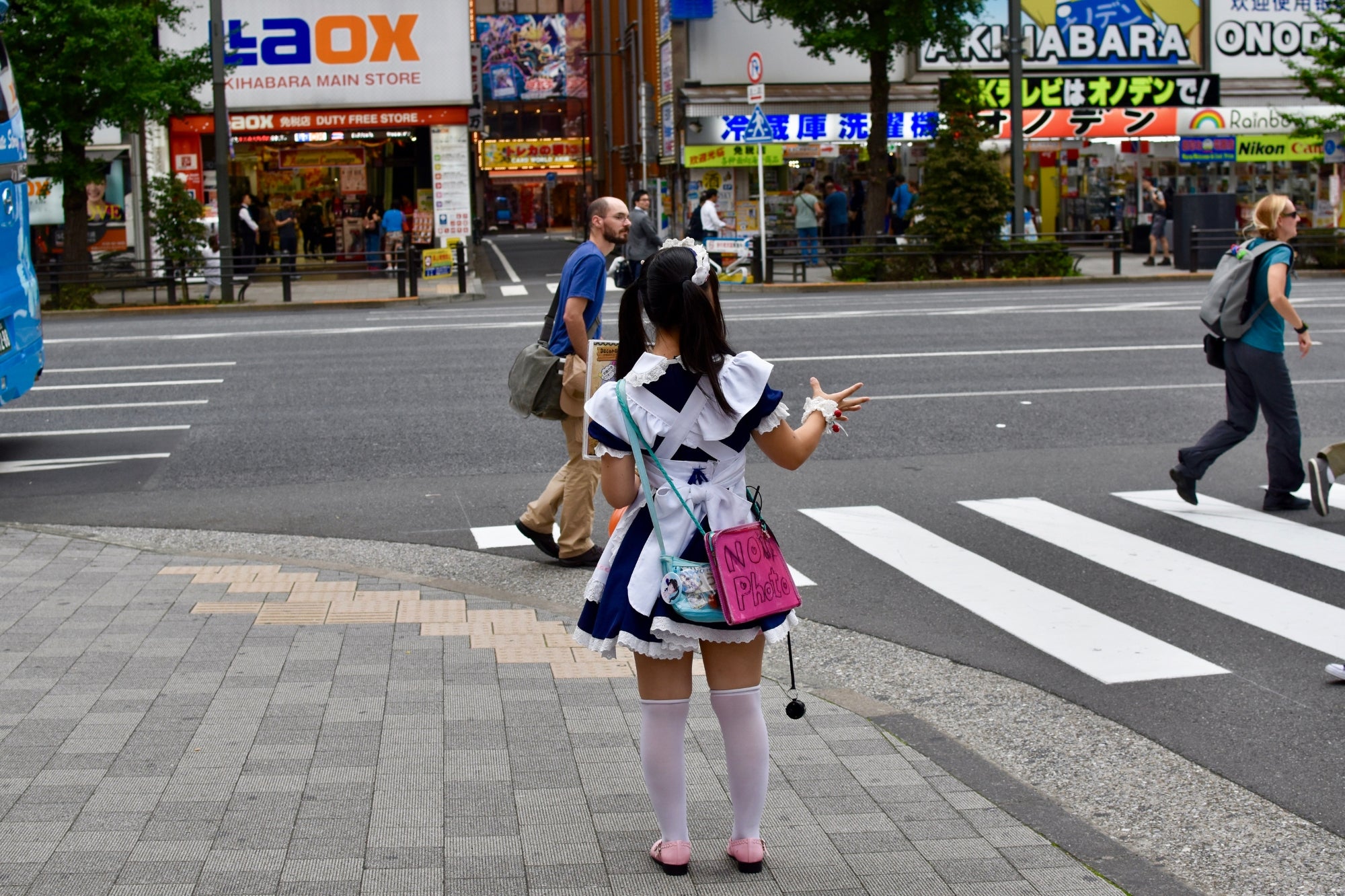 Joven vestida con uniforme de maid café en Akihabara, Tokio, invitando a los transeúntes en la calle, símbolo de la cultura otaku japonesa.