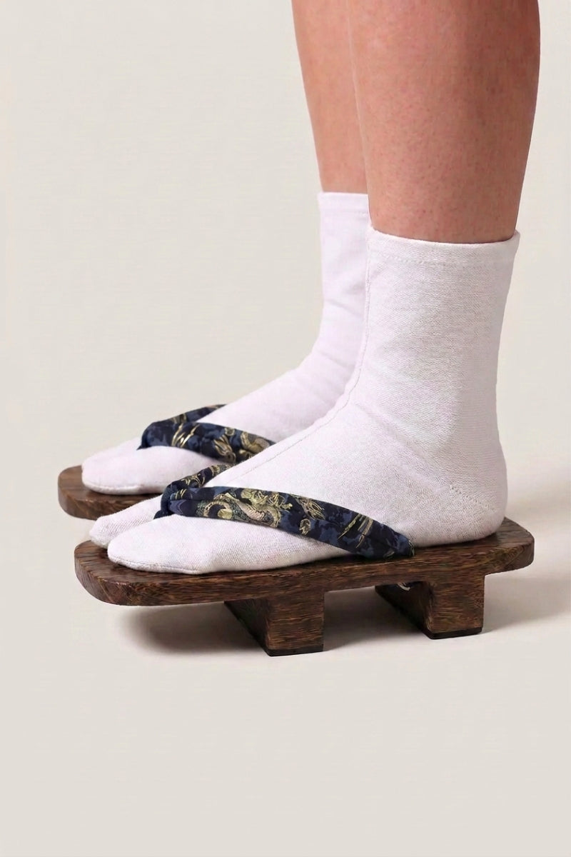 Geta japonés 'Inuyama' calzada con calcetines tabi blancos, vista de perfil — plataforma de madera oscura, tira azul noche con motivo floral dorado