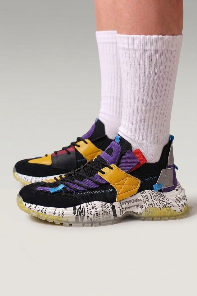 Zapatillas chunky 'Iwakura' en negro & violeta — estampado de papel de periódico, correas de color y suela teñida, con calcetines blancos en estudio