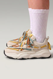 Zapatillas chunky 'Fujioka' en beige — doble cordonera multicolor y suela gruesa crema, con calcetines blancos sobre fondo de estudio gris
