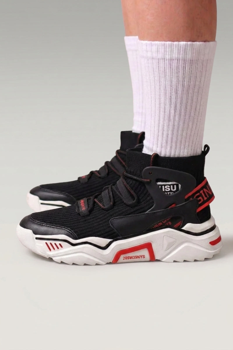 Zapatillas altas 'Echizen' en negro — dos correas anchas, cuello acolchado y detalles rojos, con calcetines blancos sobre fondo de estudio gris
